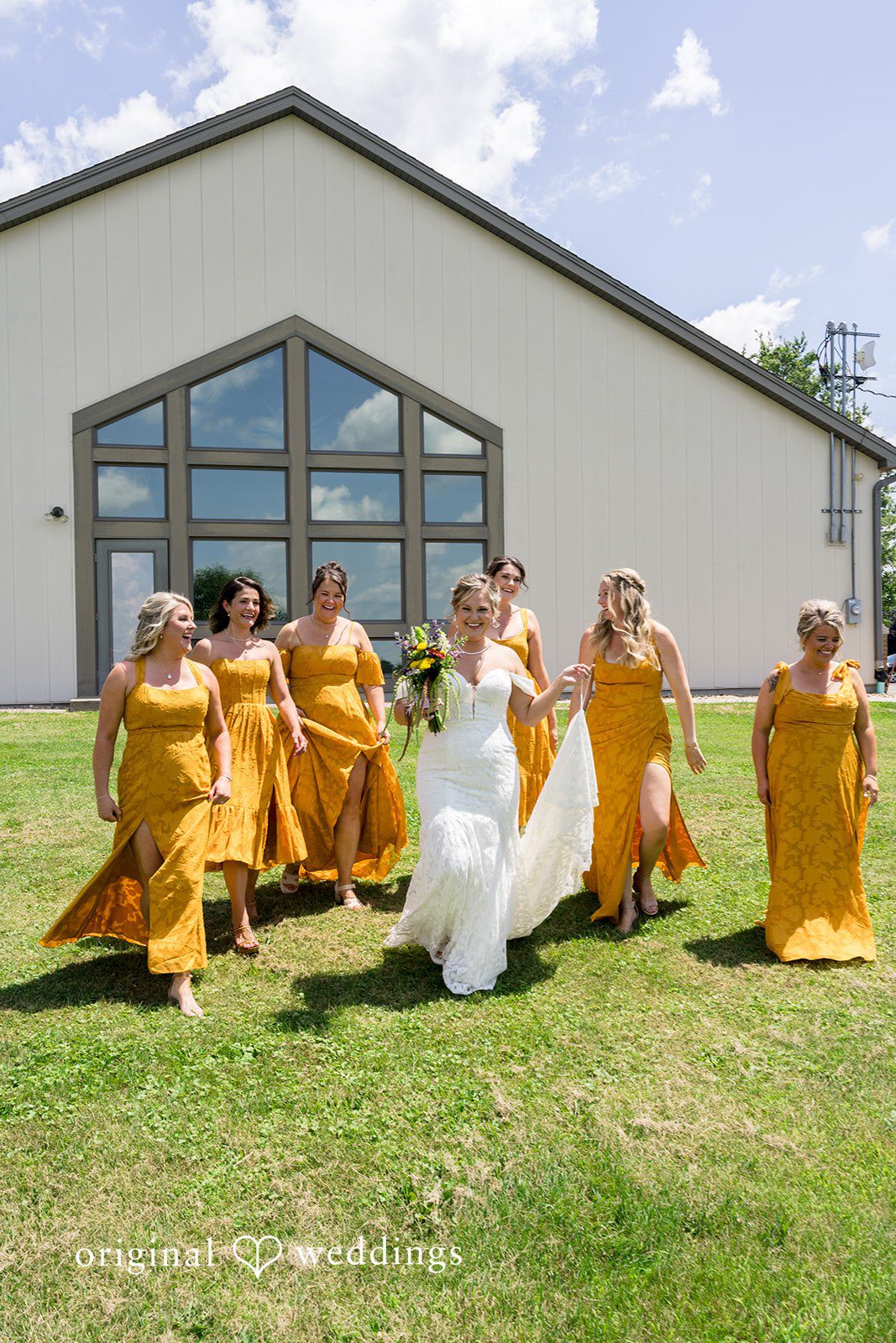A wedding party joyfully tossing flower petals in the air on a sunny green lawn.
