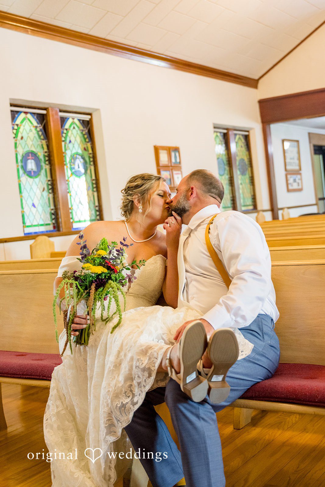 A bride and groom sitting closely together at a rustic wedding reception table.