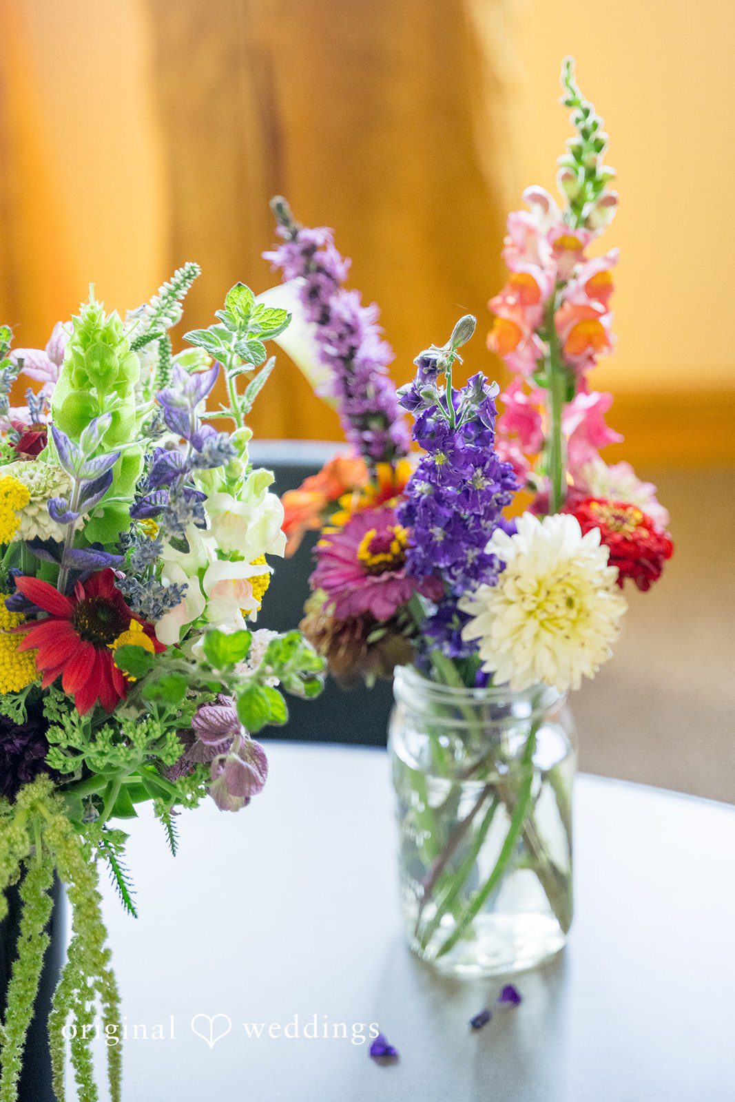 A colorful bouquet of wildflowers arranged inside a clear glass jar on a table.