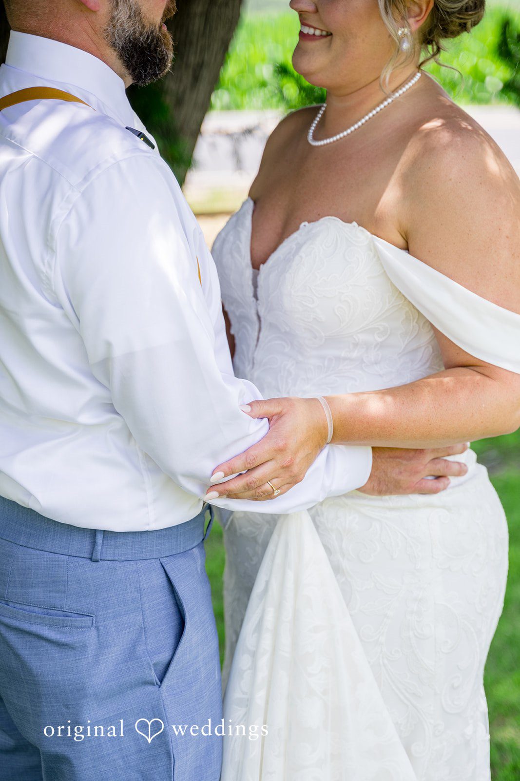 A close-up view of a bride and groom holding hands during their wedding photoshoot.