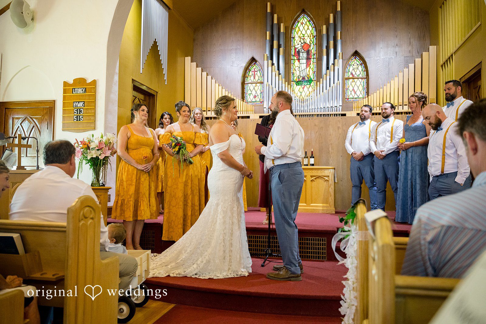 A wedding ceremony taking place at the altar of a church with guests watching from the pews.