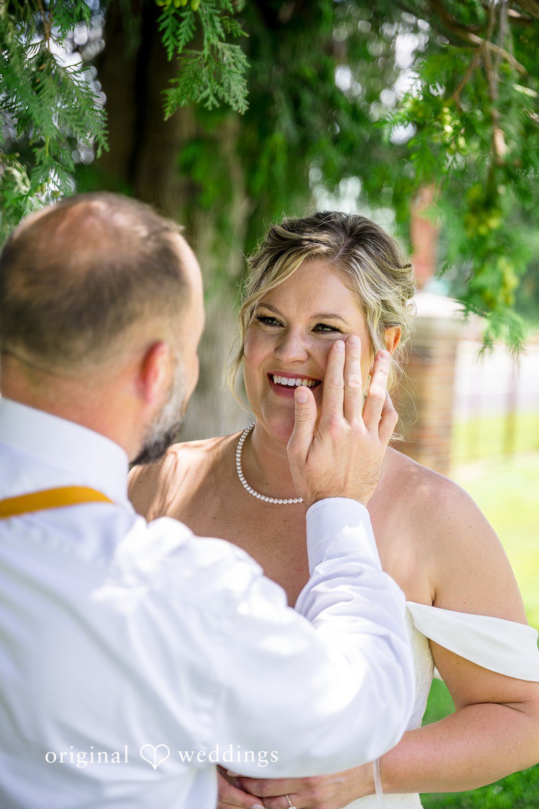 A groom gently wiping a tear from his bride's face during an emotional moment.