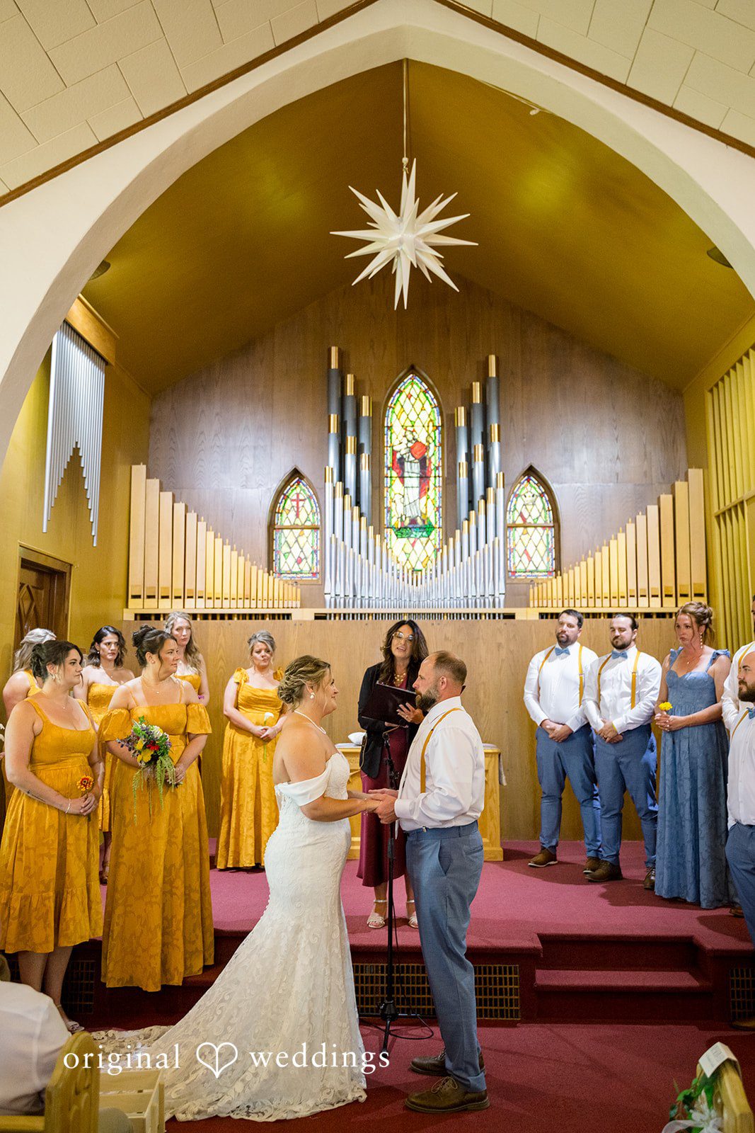 A wedding ceremony underway inside a church sanctuary illuminated by warm lighting.