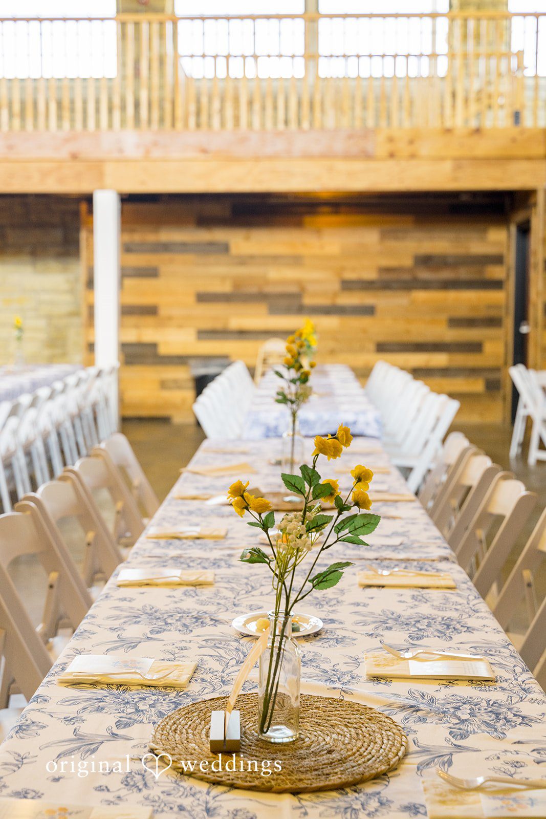 A long wooden banquet table beautifully decorated with floral centerpieces and table runners.