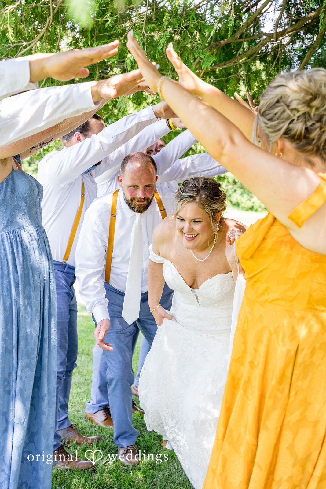 The wedding party creating a tunnel with their raised hands for the bride and groom to run through.
