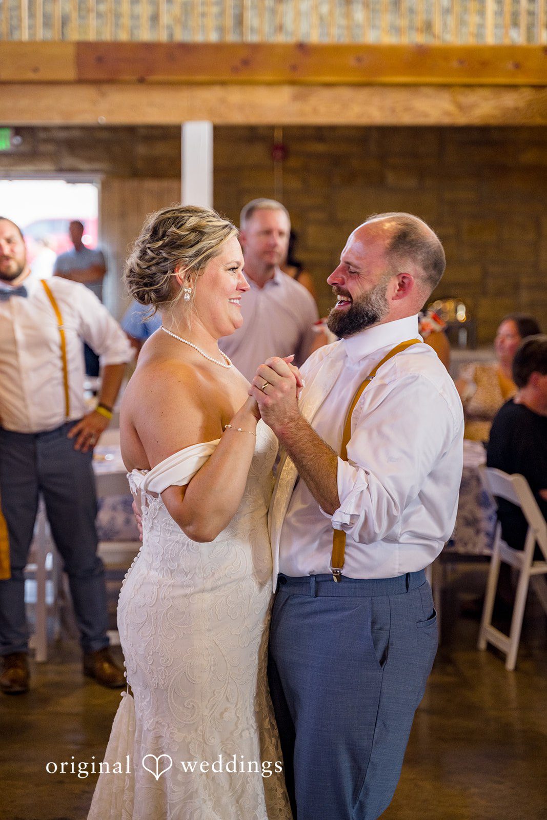 A bride and groom smiling at each other while dancing together during their wedding reception.