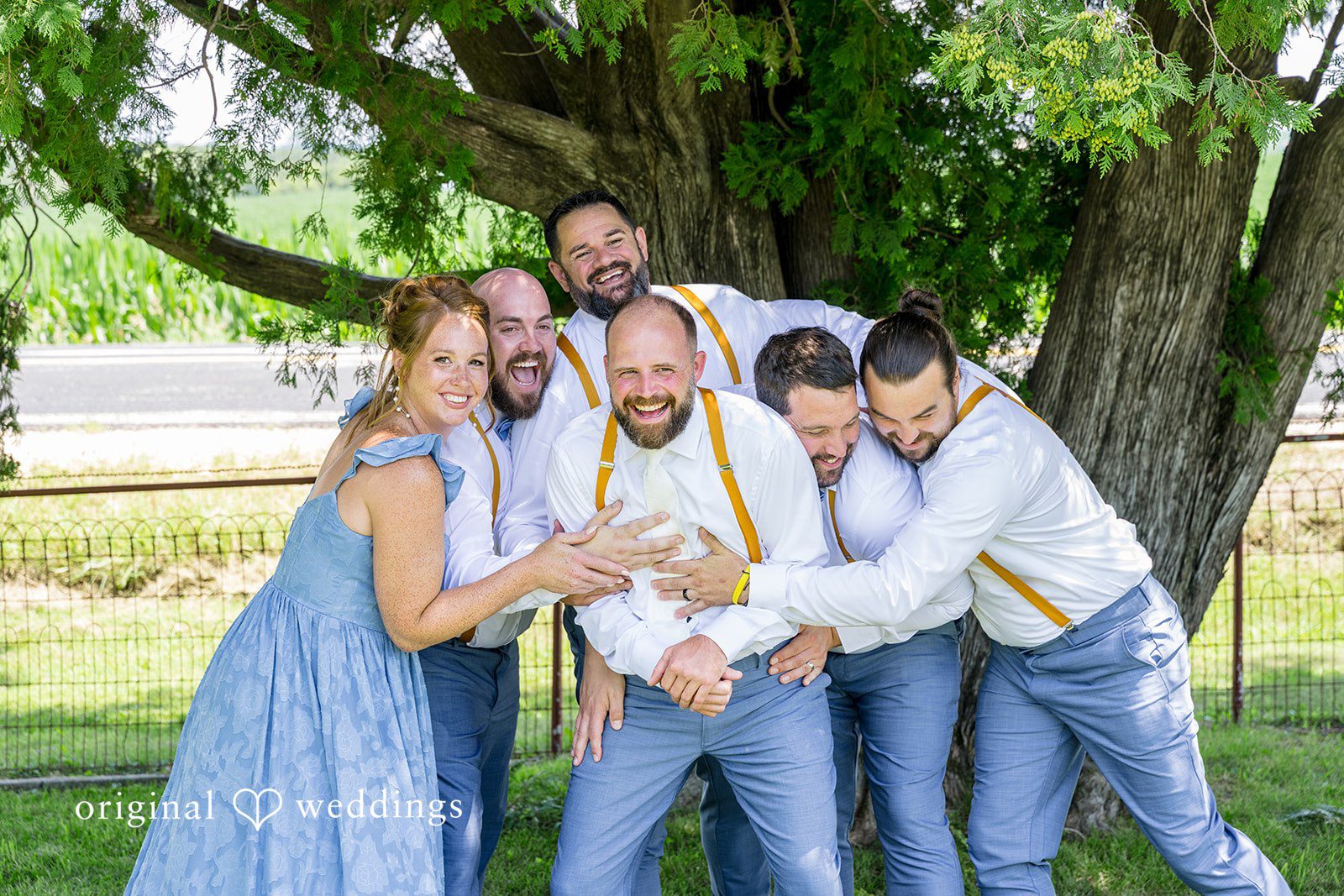 Groomsmen and bridesmaids leaning in close together for a fun group photo.