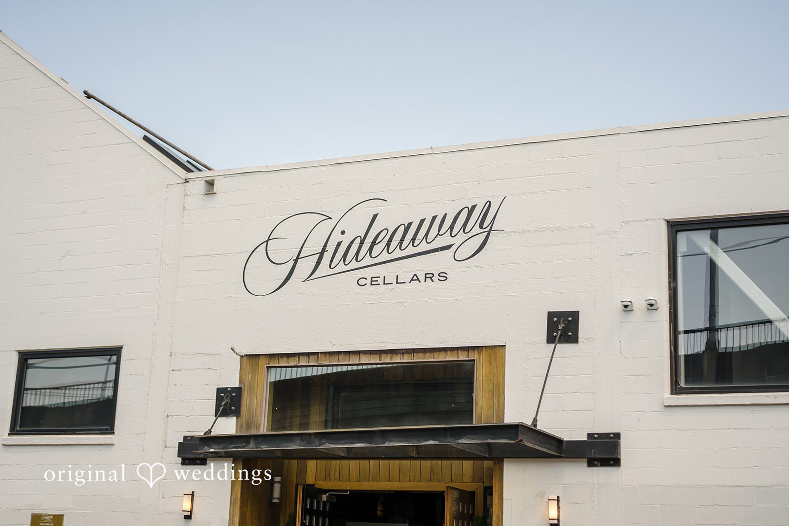 An exterior shot of a white building with the name "Hideaway Cellars" written above the entrance.