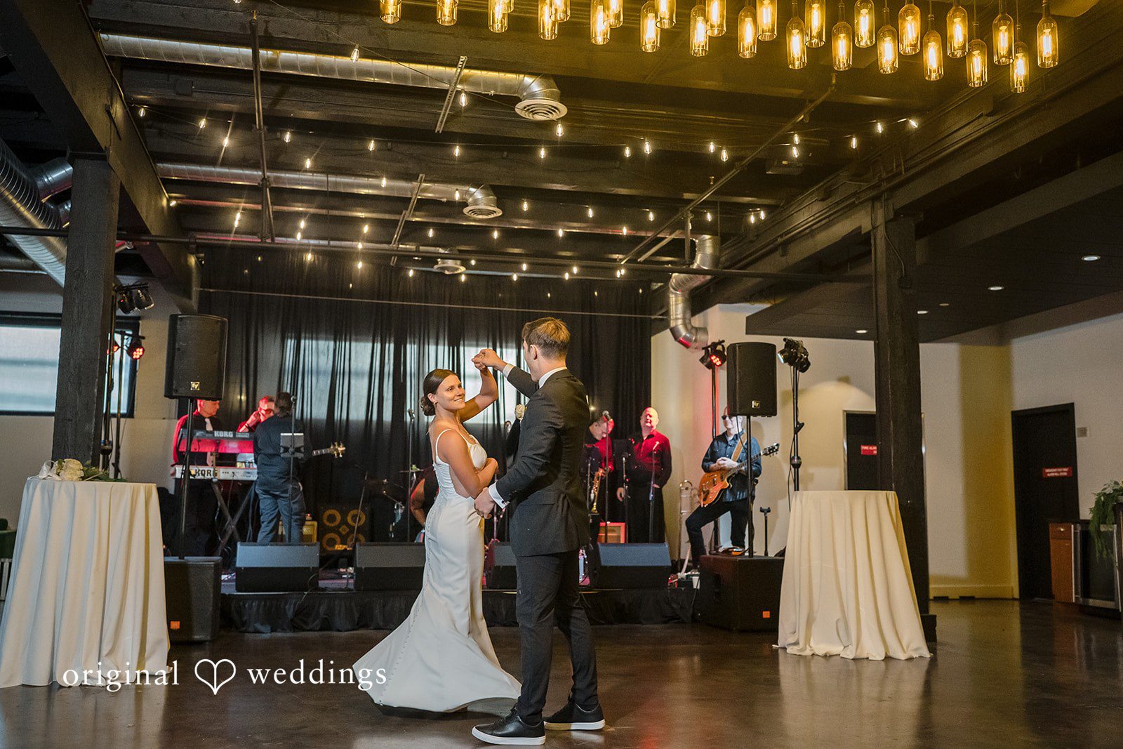 A newlywed couple shares their first dance on a spacious dance floor.