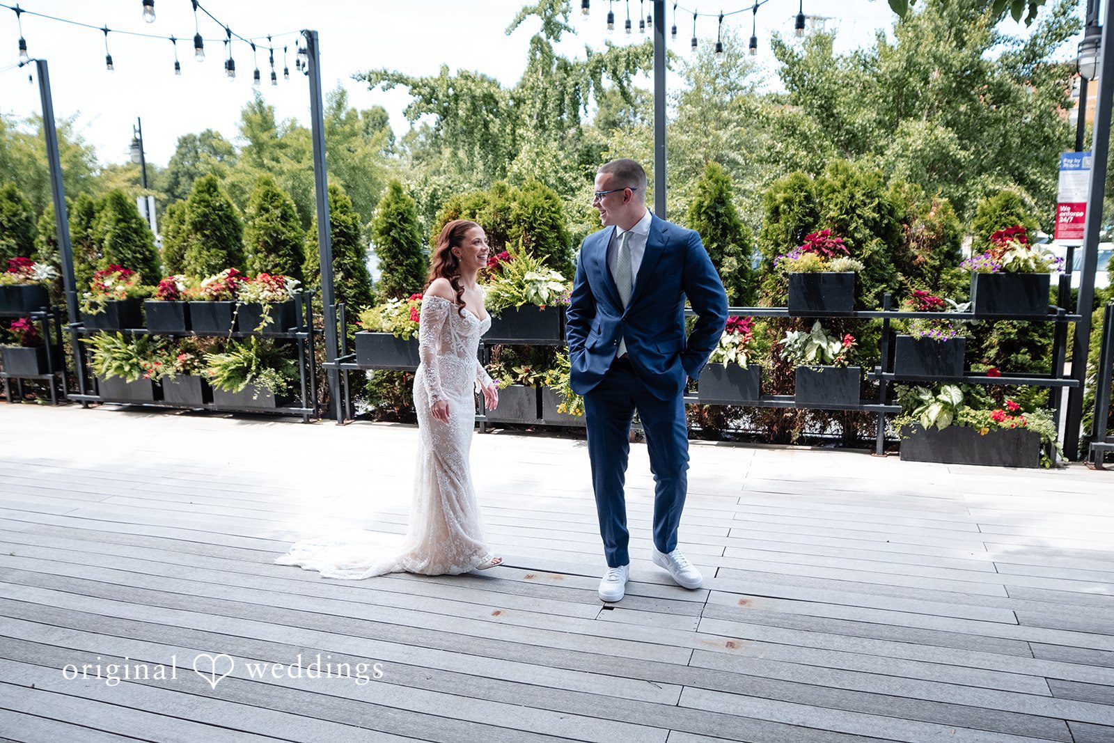 Lucy + Cormac A bride and groom standing together on a paved walkway.
