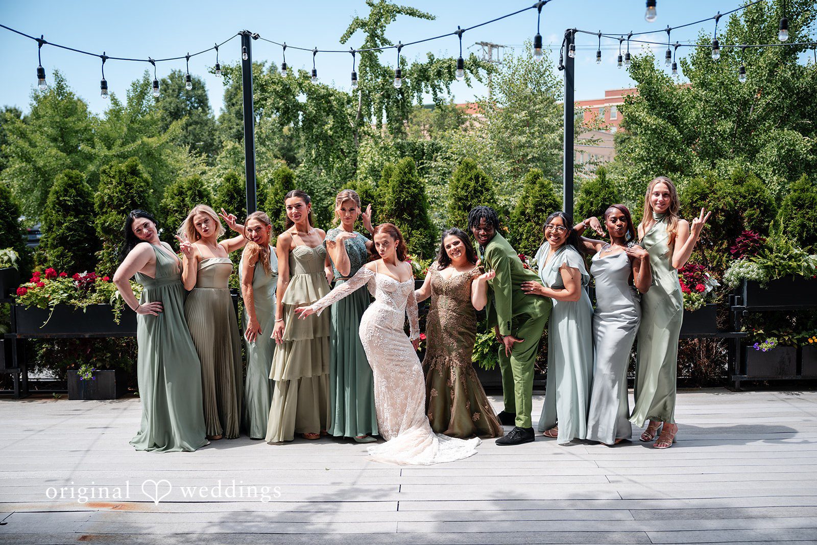 Lucy + Cormac A wedding party posing together against a background of green trees.