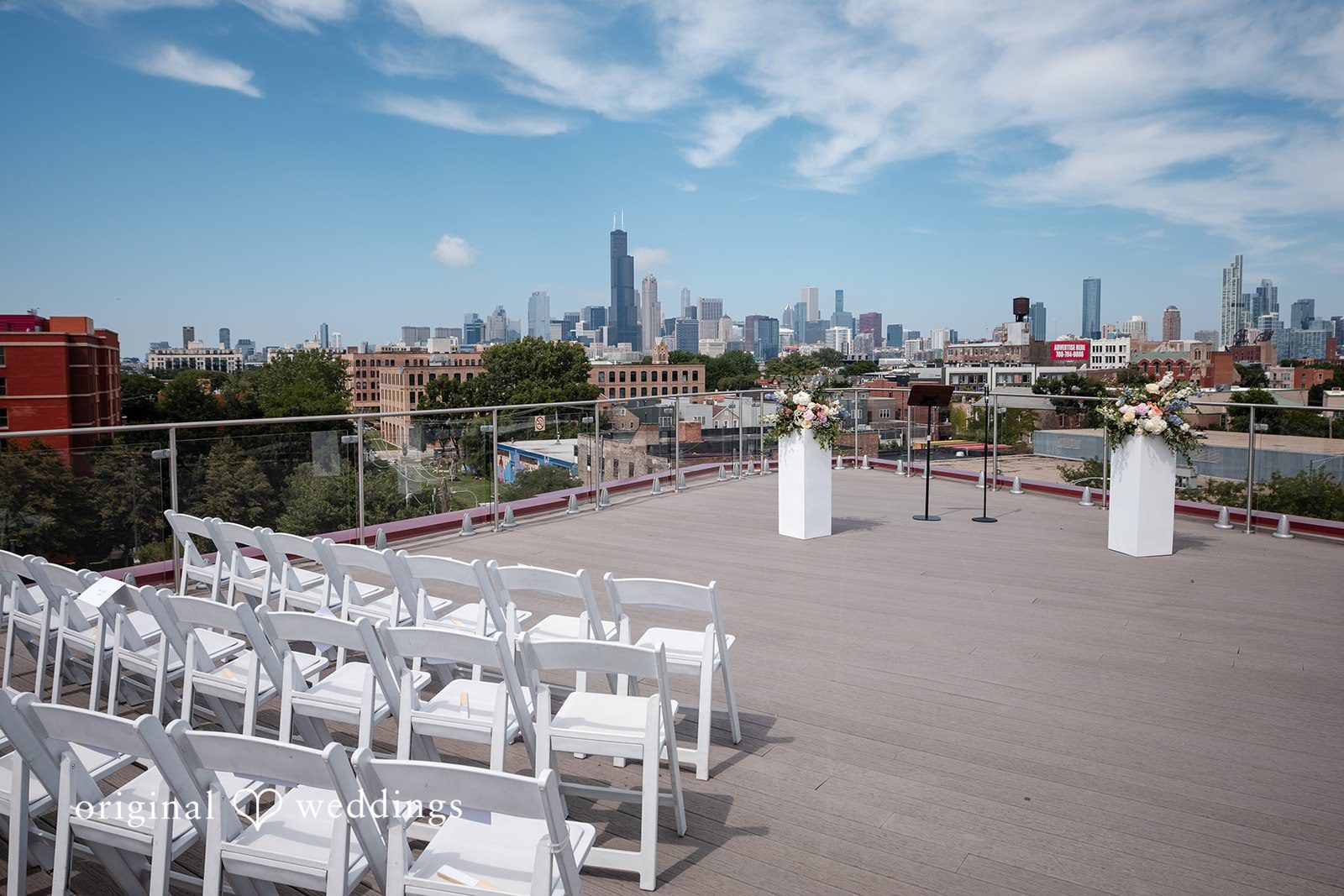 Lucy + Cormac White chairs set up on a rooftop terrace overlooking a city skyline.