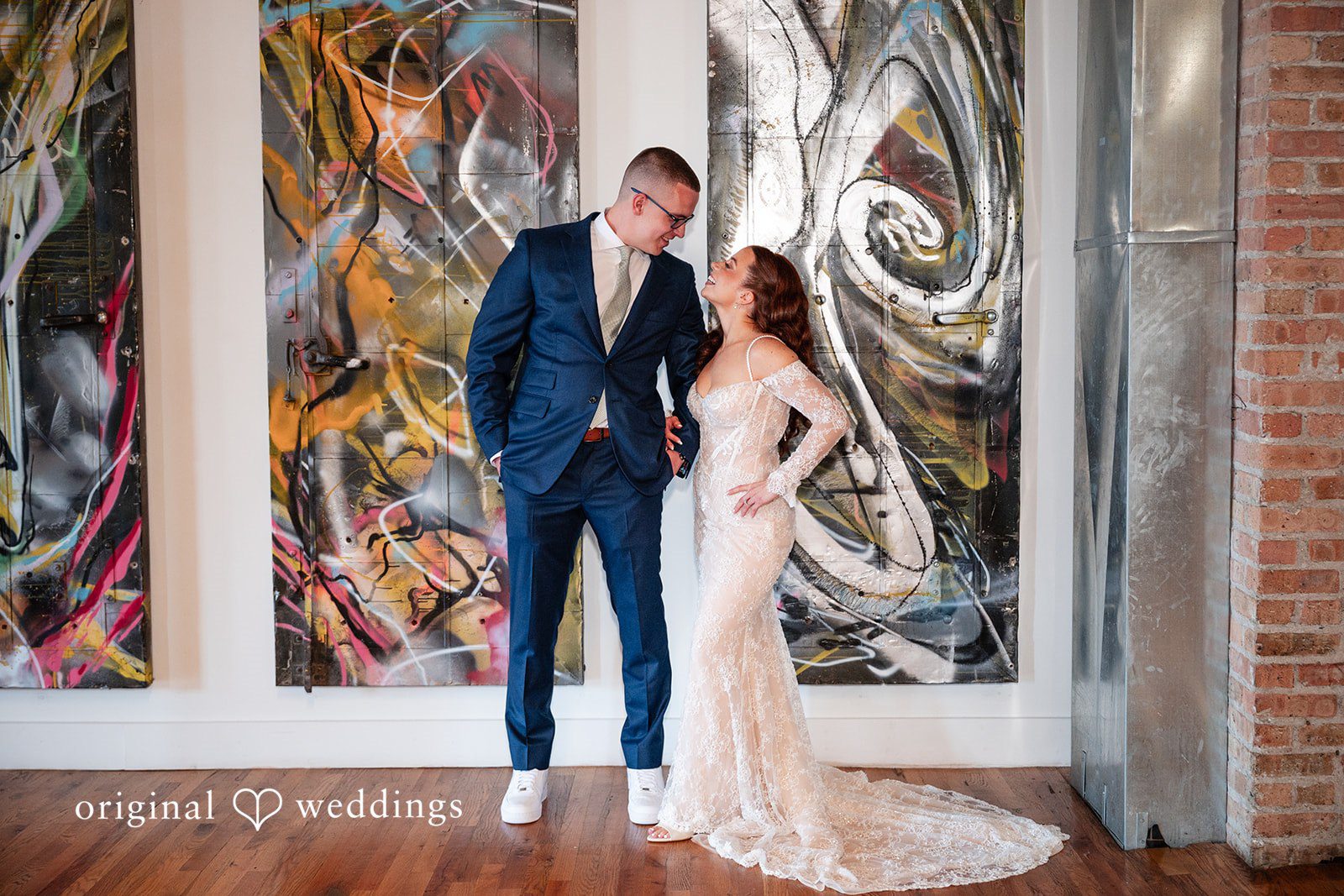 Lucy + Cormac A bride and groom standing in front of an abstract mural wall.