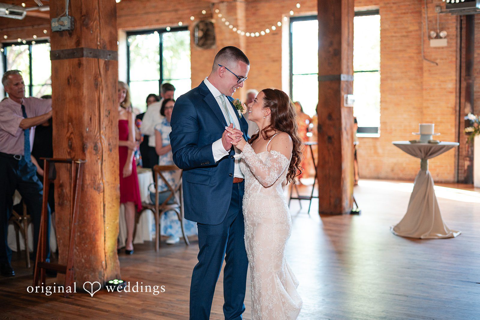 Lucy + Cormac A bride and groom dancing together inside a room with large windows.