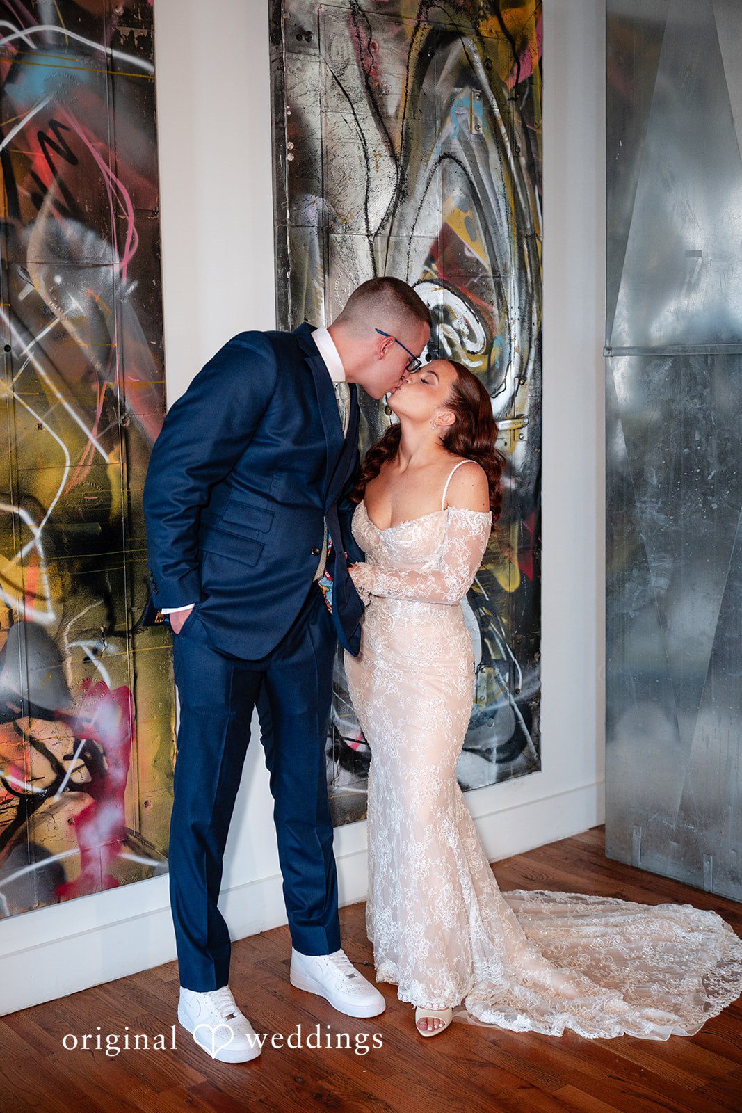 Lucy + Cormac A bride and groom embracing and leaning back against a painted wall.