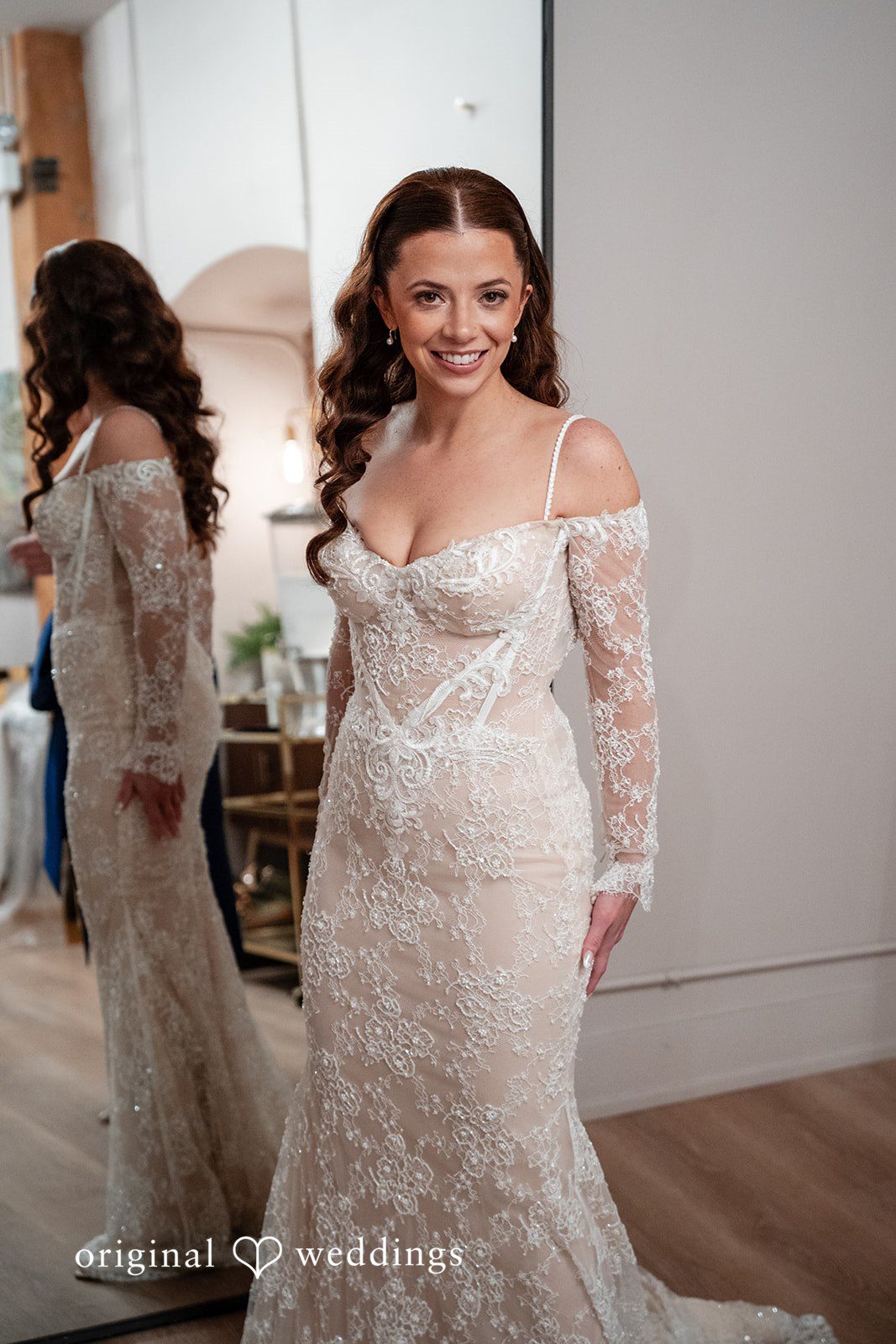 Lucy + Cormac A bride in a lace wedding gown walking inside a room.