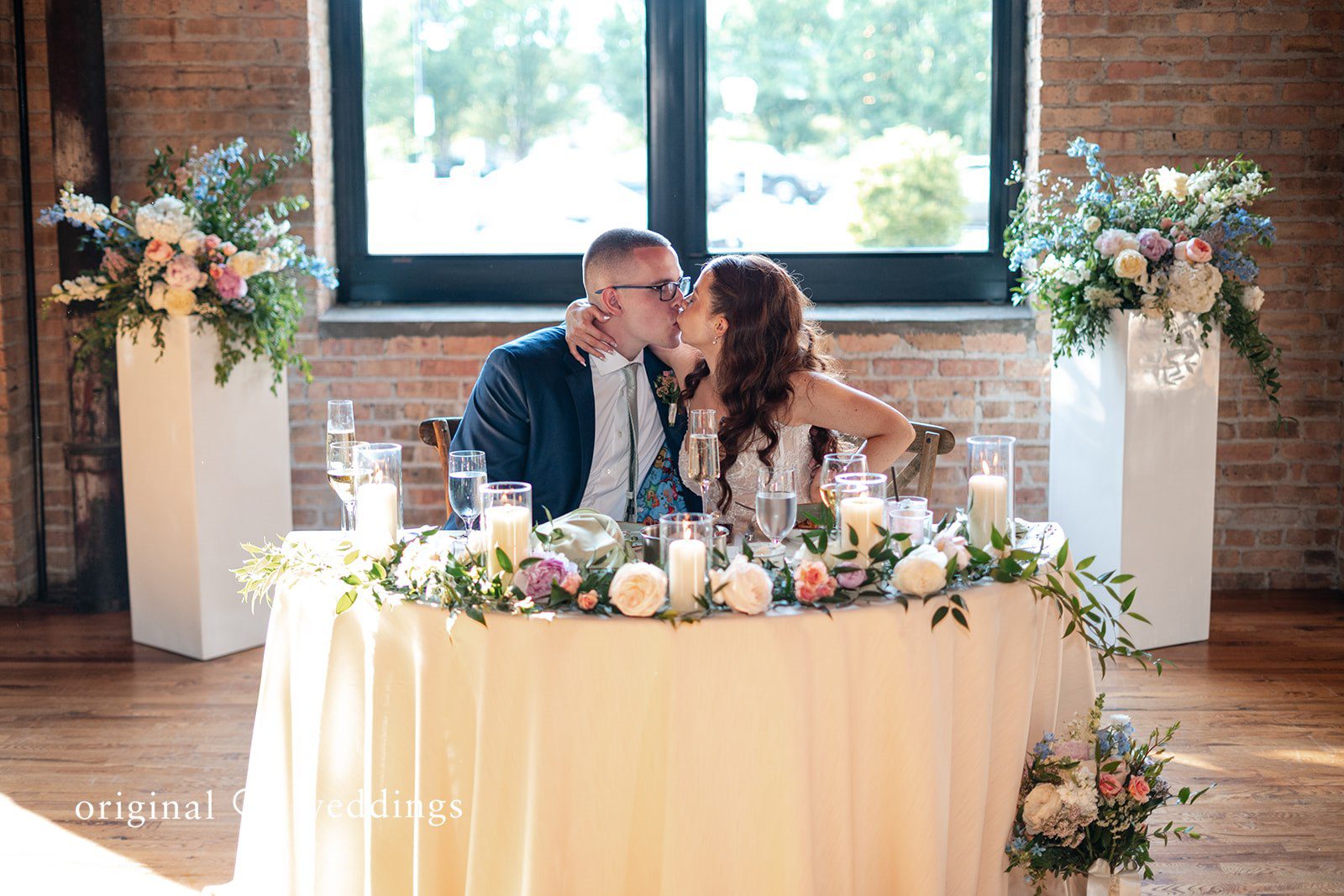Lucy + Cormac A bride and groom kissing and sitting in a decorated head table.