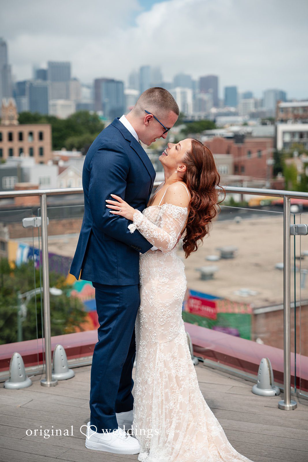 Lucy + Cormac A bride and groom embracing on a rooftop terrace with a city view.