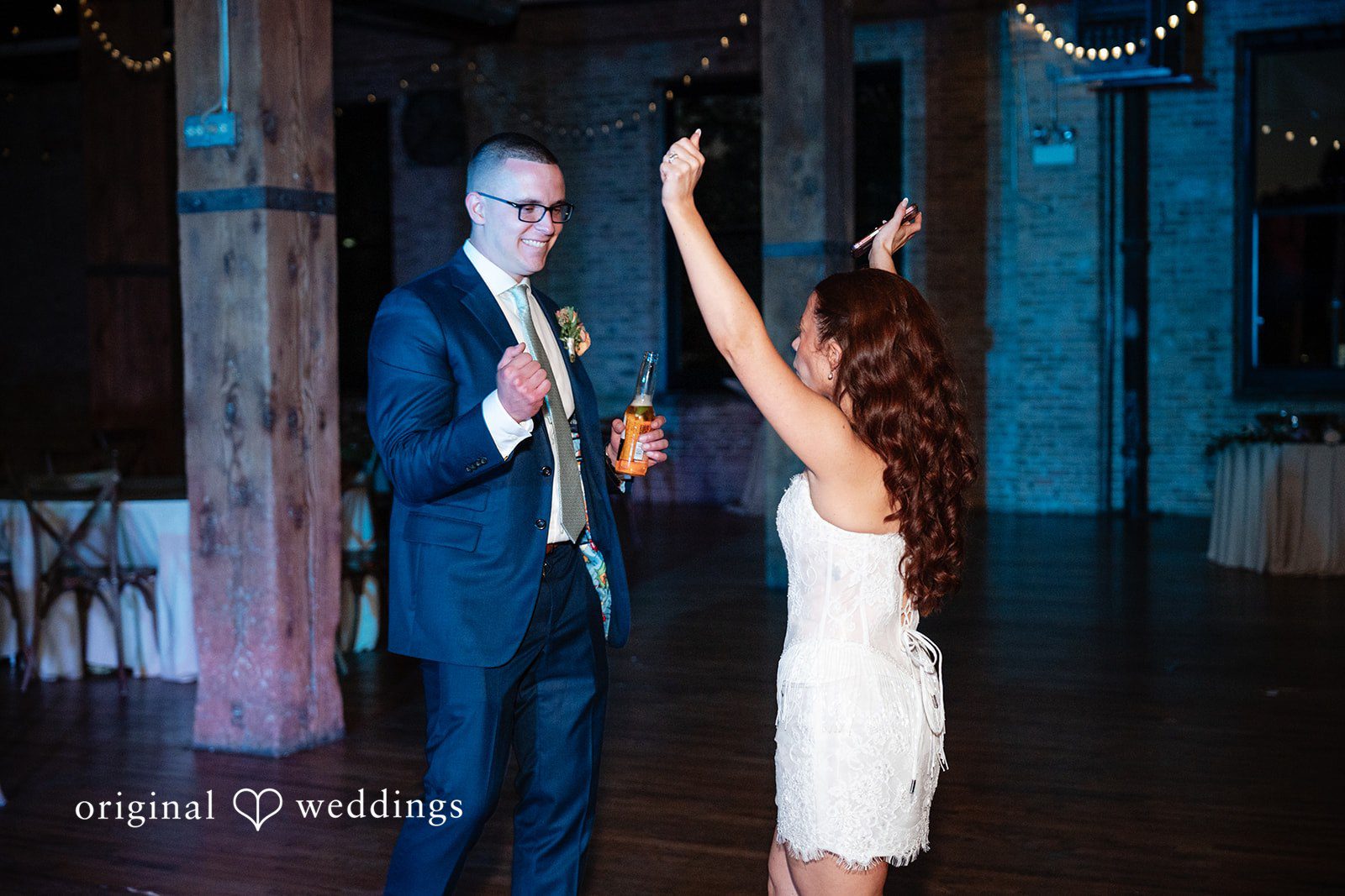 Lucy + Cormac A bride dancing with her arms raised while the groom stands nearby.