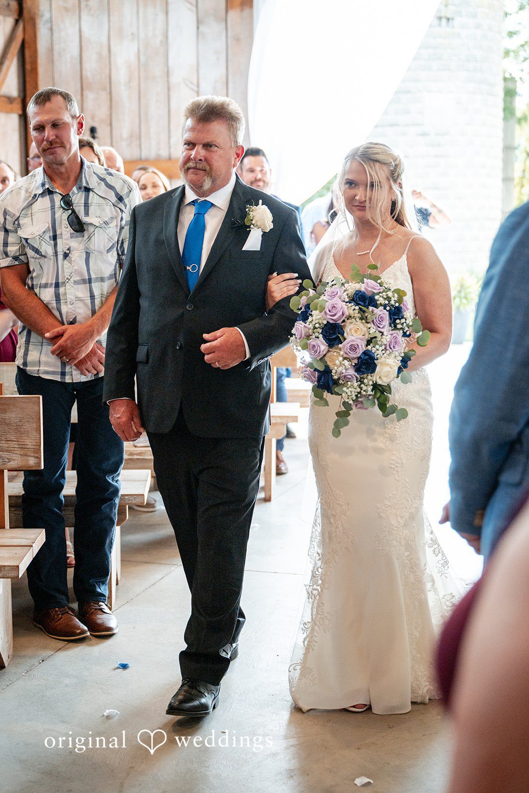 A bride walking down the aisle escorted by a man.