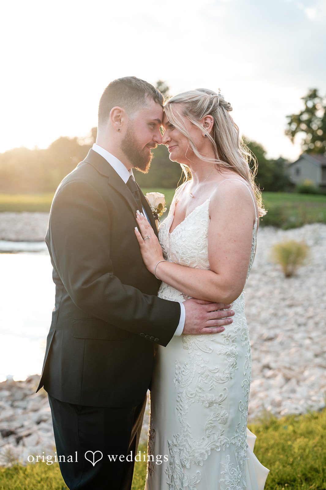 A bride and groom holding each other and smiling during a portrait session at sunset.