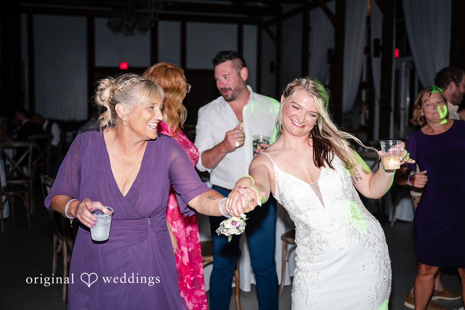 Wedding guests cheering and dancing dynamically on a crowded dance floor.