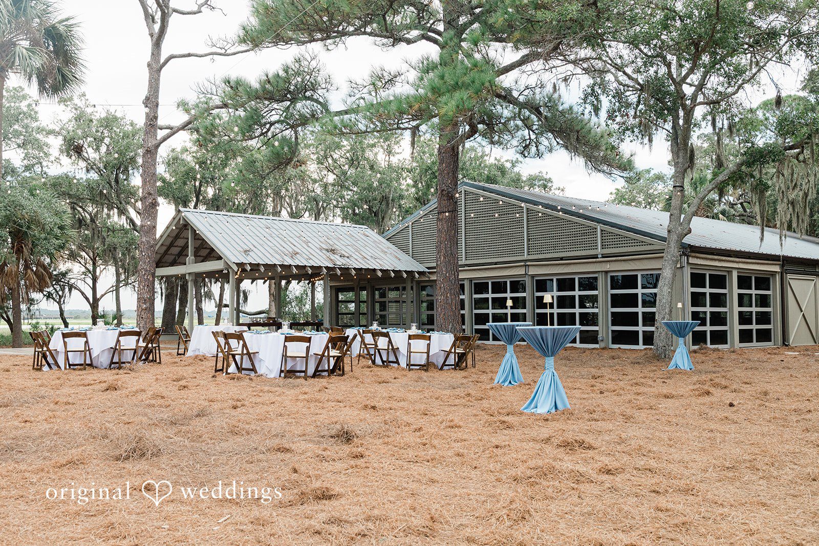 Jennifer + Zac An empty wedding reception setup under a transparent canopy tent with round tables and white chairs.