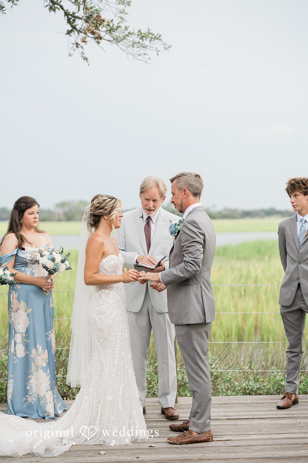 Jennifer + Zac A bride and groom standing together during their wedding ceremony with guests looking on.