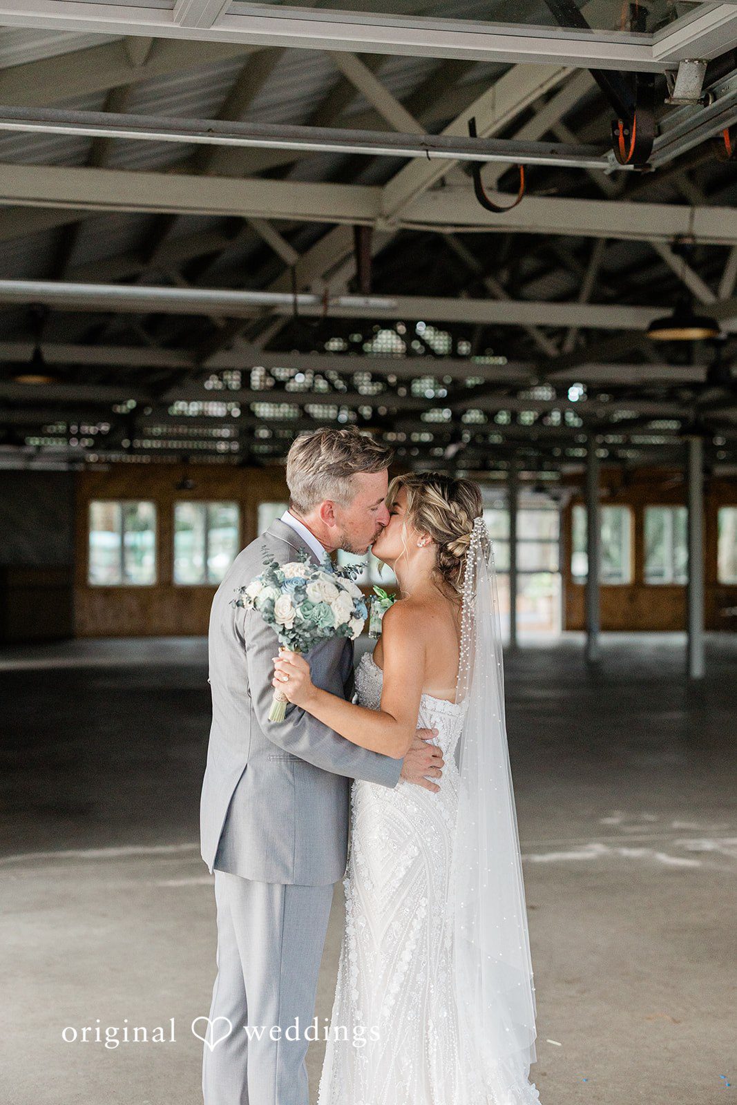 Jennifer + Zac A bride and groom sharing a kiss inside a rustic wooden barn venue.