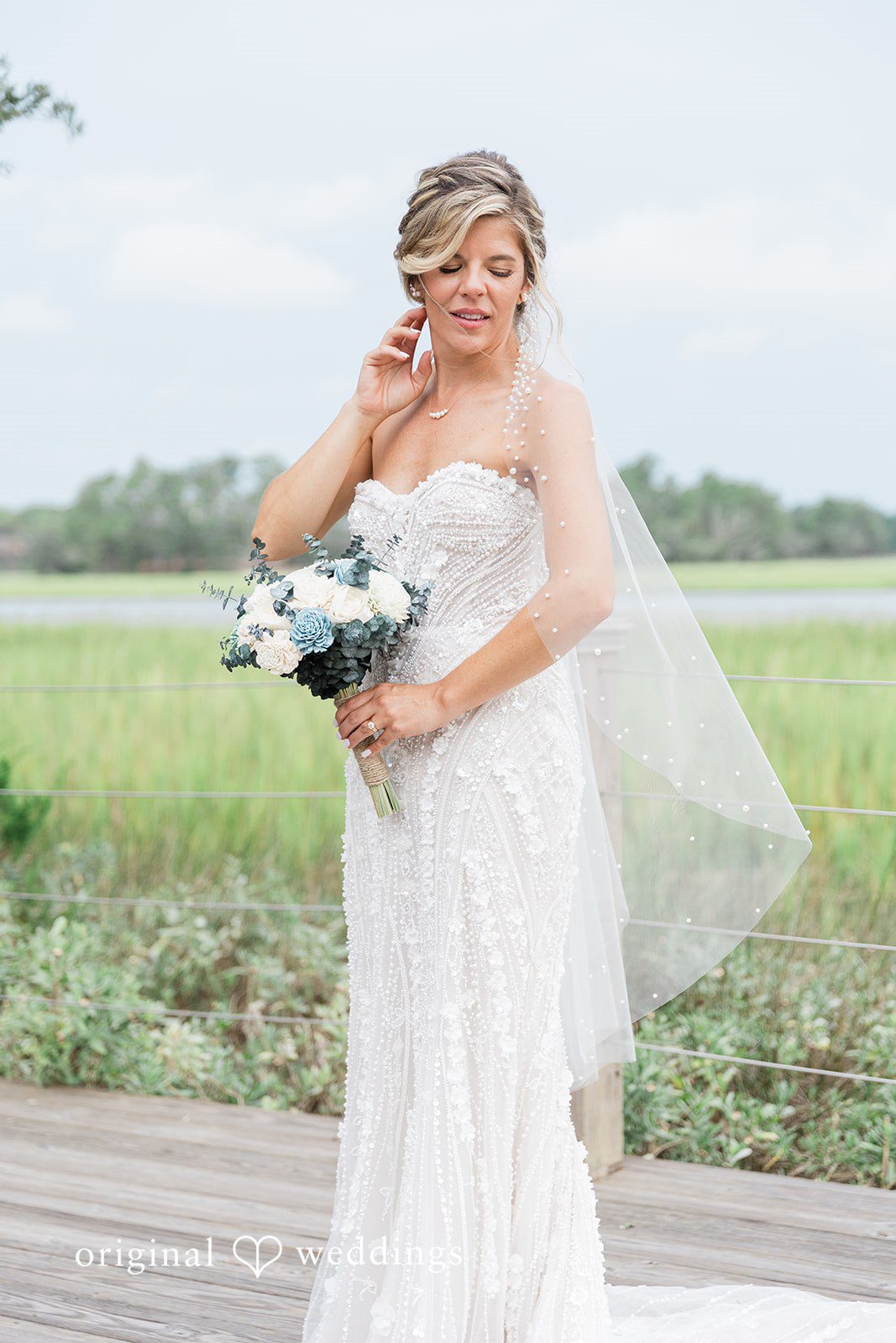 Jennifer + Zac A bride in a white gown posing while smiling in an open grassy landscape.