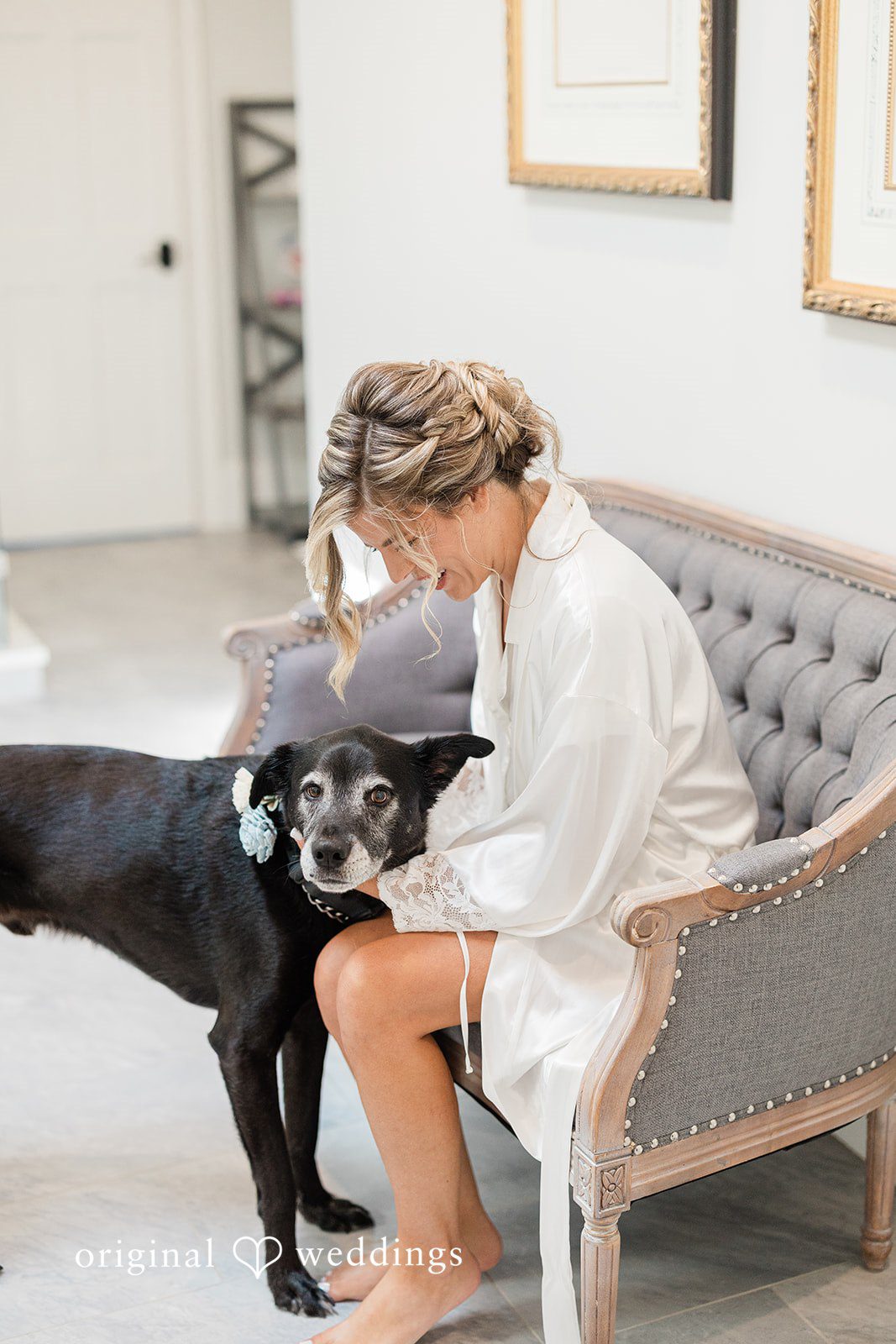 Jennifer + Zac A bride in a silk robe sitting on a couch while petting a black dog next to her.