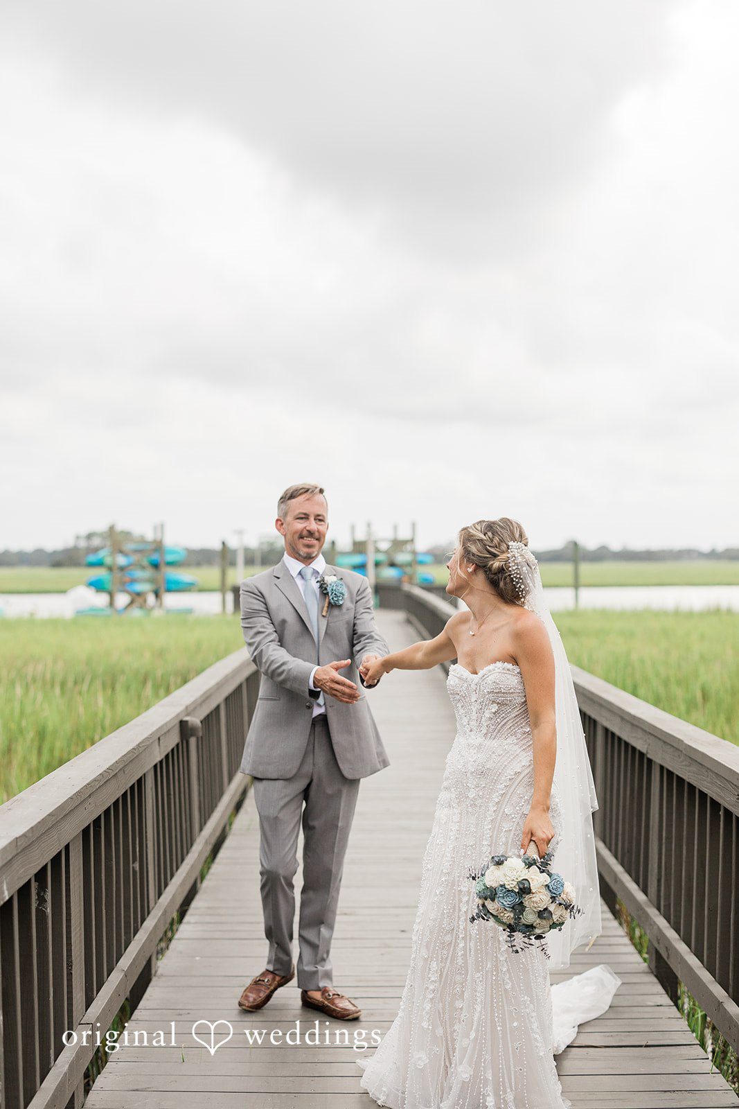 Jennifer + Zac A bride and groom walking hand-in-hand down a wooden walkway.