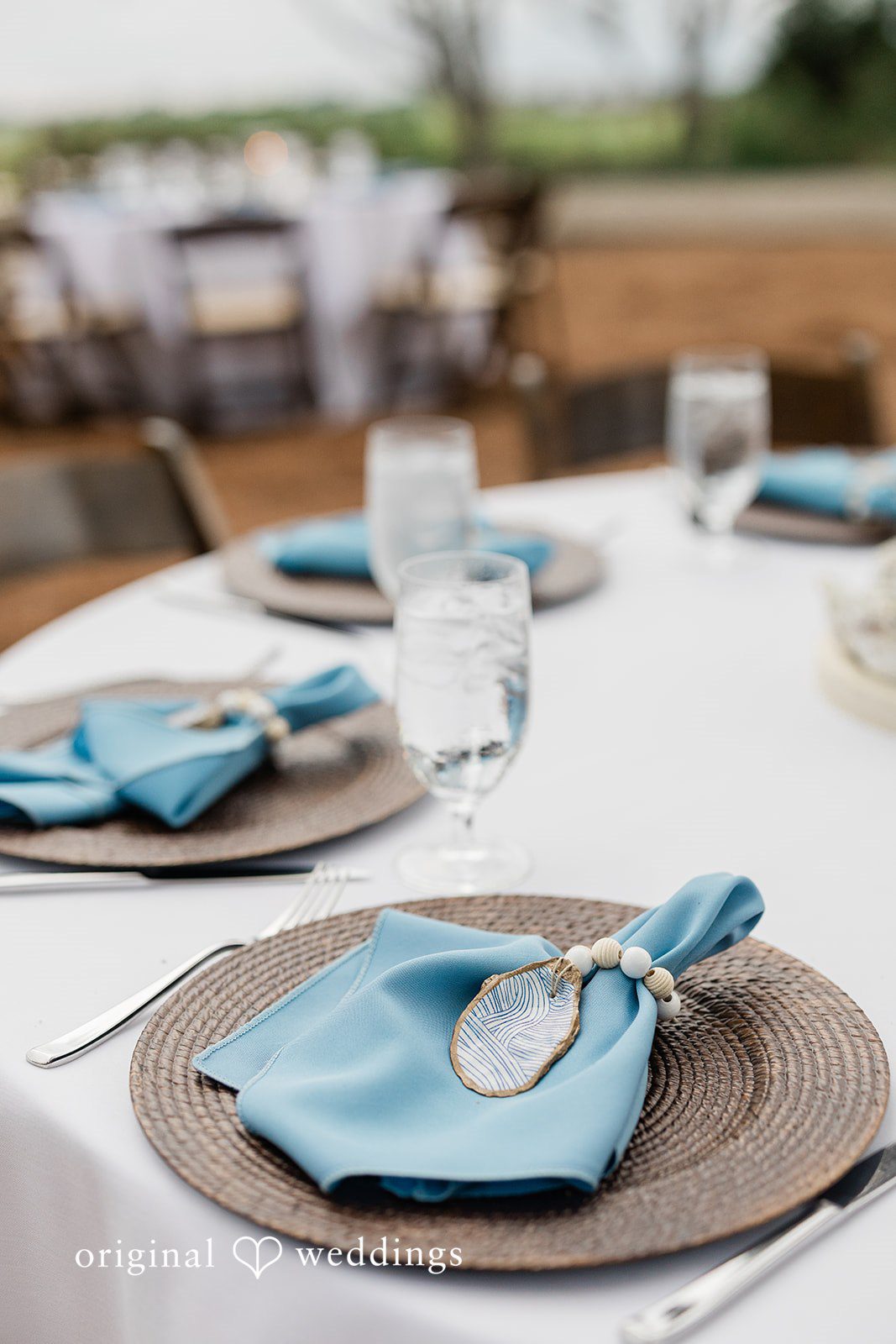 Jennifer + Zac A close-up of a wedding reception table setting featuring a light blue napkin, a plate, and a menu card.