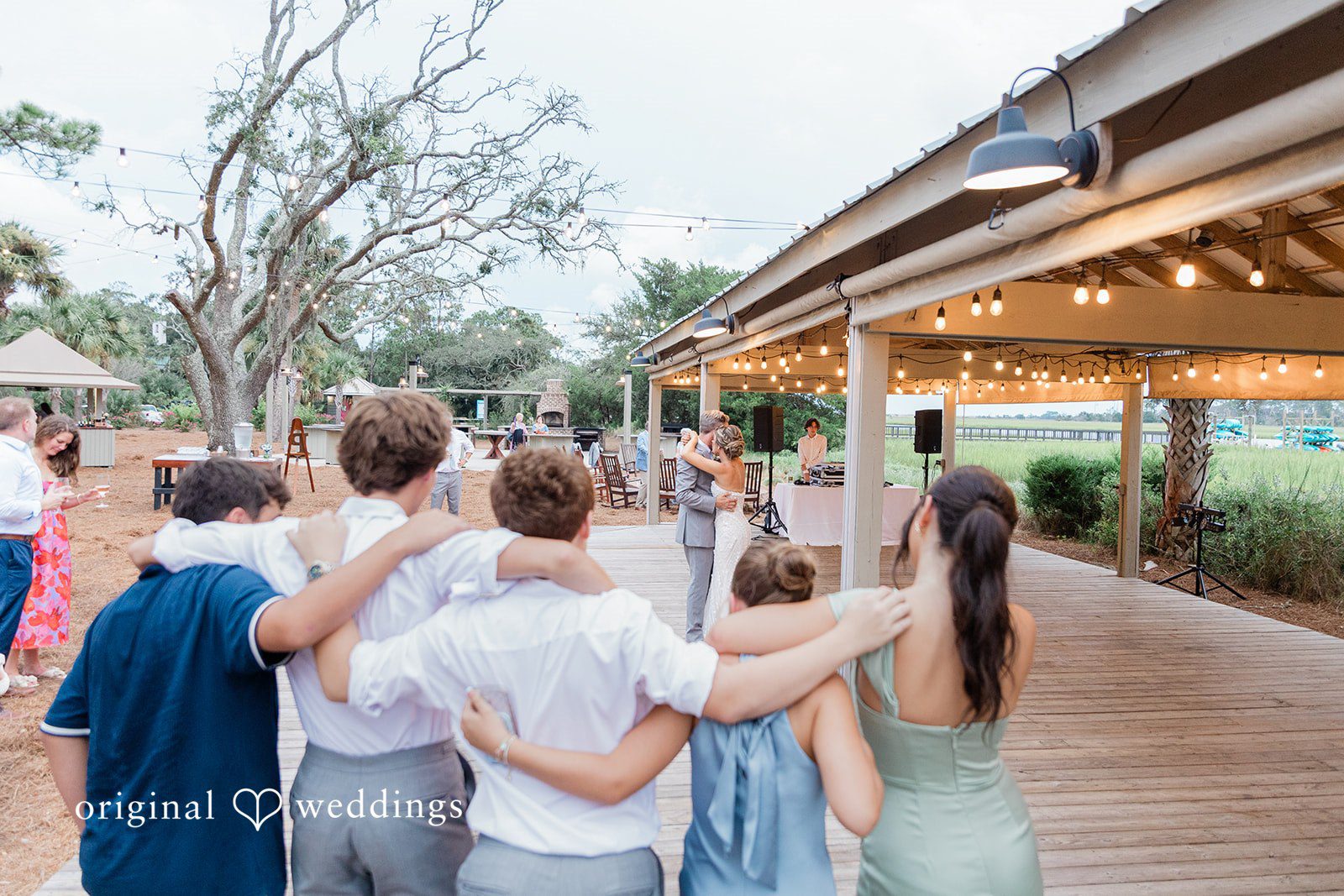 Jennifer + Zac A group of wedding guests chatting under a decorated pavilion.
