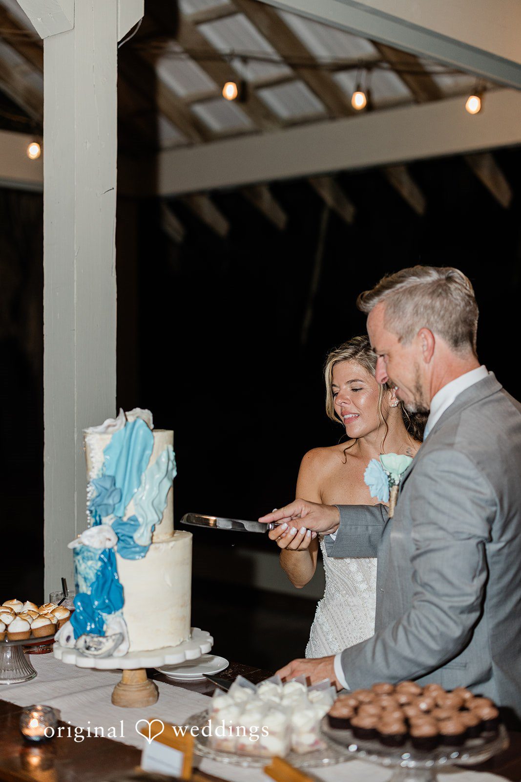 Jennifer + Zac A bride and groom standing together behind their wedding cake at the reception.