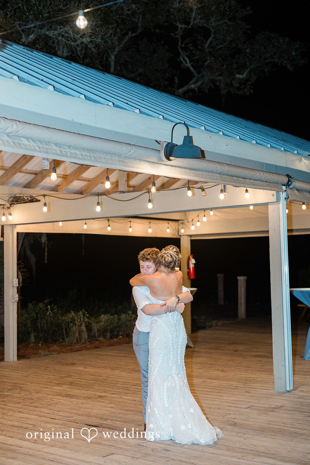 Jennifer + Zac A bride in a white gown and a young boy in a grey suit slow dancing at an illuminated reception.
