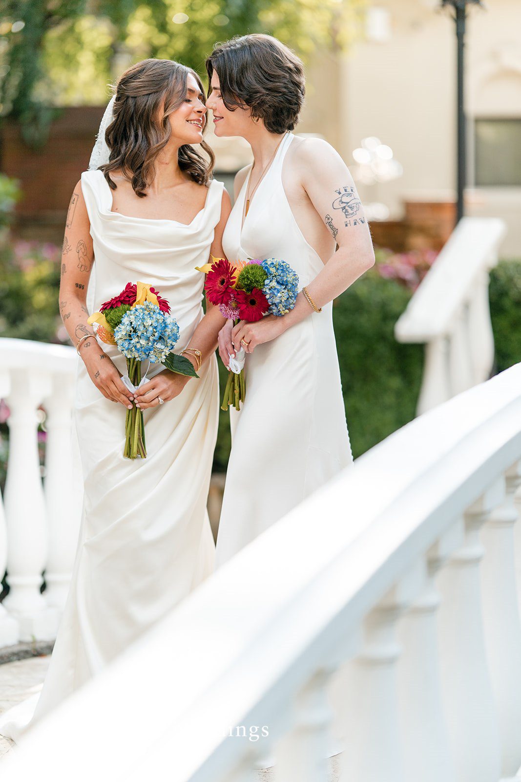 Couple standing together and smiling at each other by a white railing.