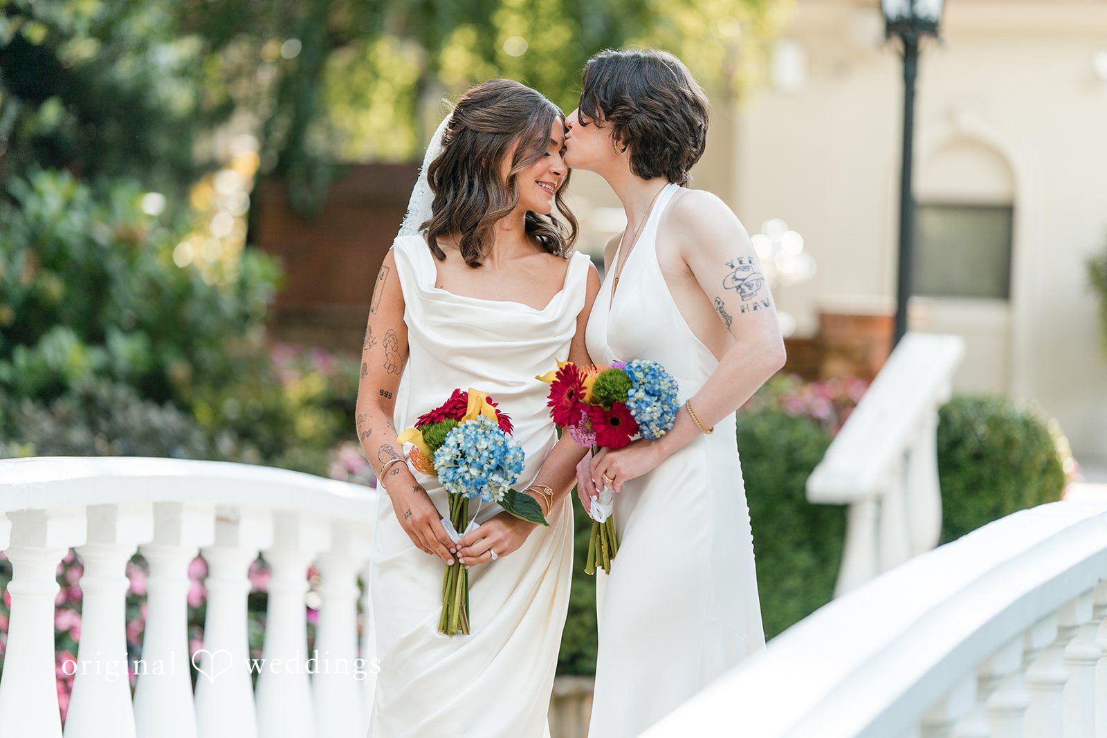 A couple holding hands and walking down an aisle lined with white railings.
