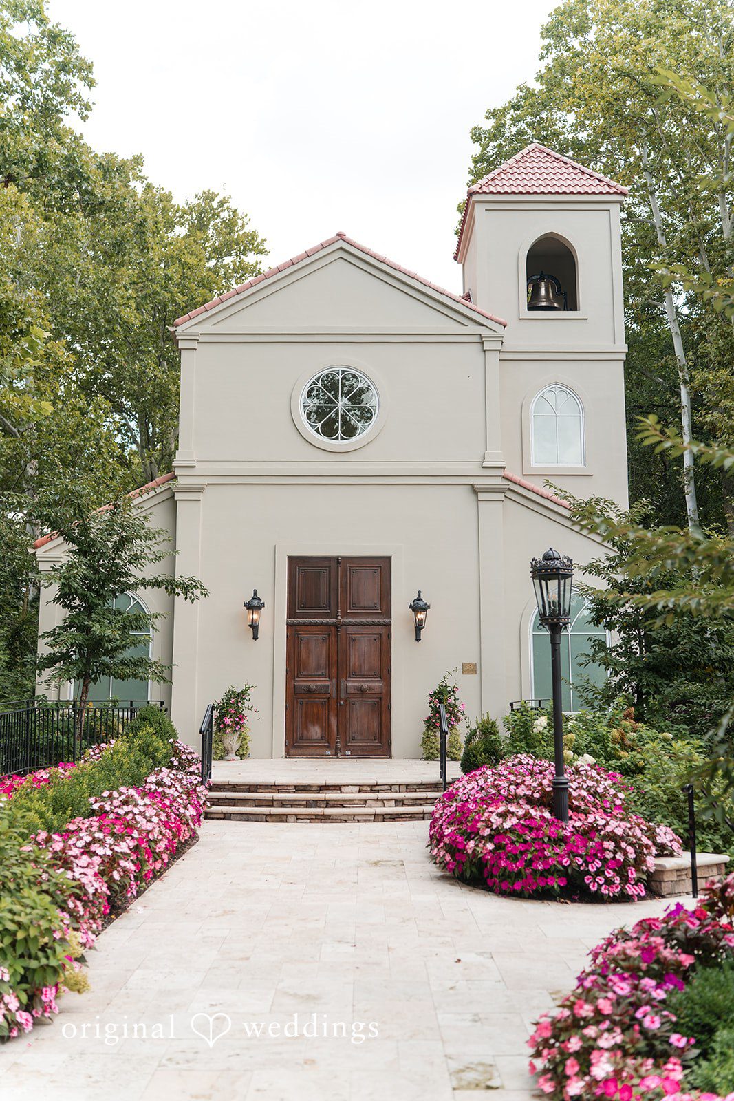 The front entrance of a white church with arched windows and manicured landscaping.