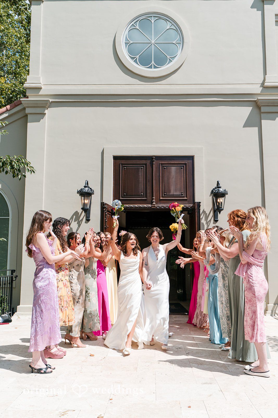 A large group of wedding guests celebrating and throwing flower petals in the air.