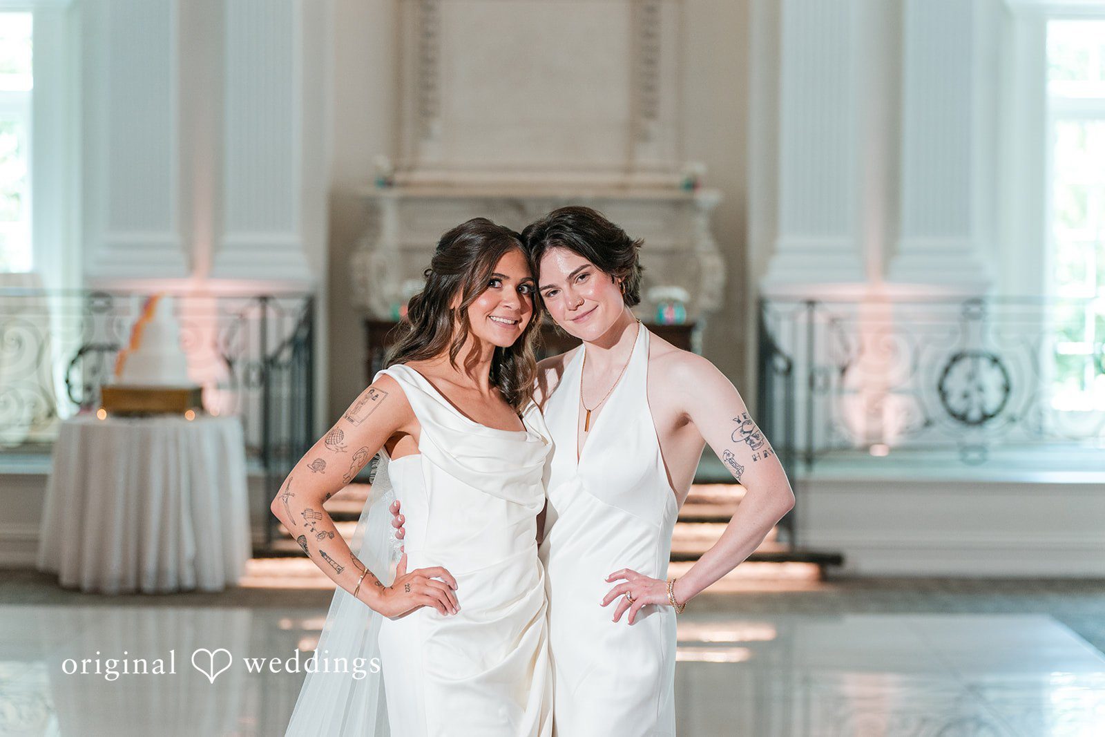 Couple standing side-by-side in front of a fireplace mantel, smiling at the camera.