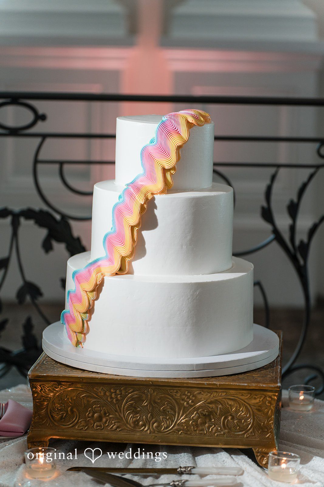 A three-tiered white wedding cake decorated with a cascading trail of orange flowers.