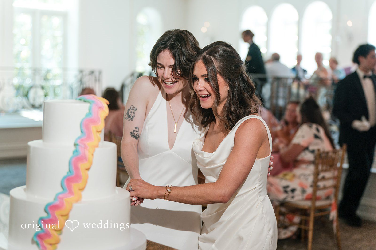 Couple smiling together while standing and cut a wedding cake.