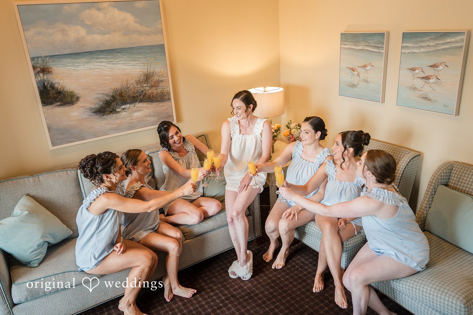 Daniel + Karen A bride and her bridesmaids in matching robes celebrating together on a bed.