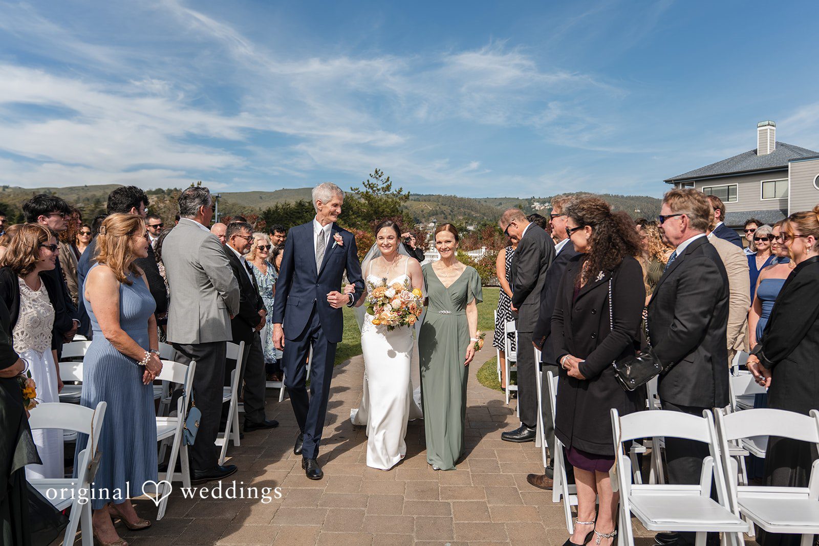 Daniel + Karen Wedding guests standing together and bride walking down an aisle with guest.