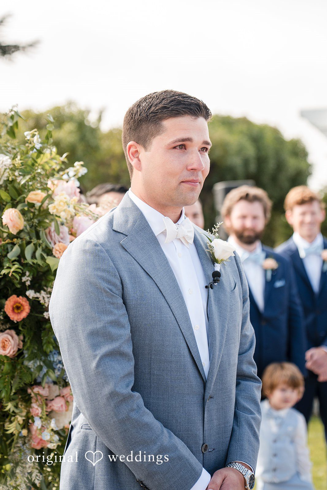 Daniel + Karen A groom in a grey suit looking forward attentively during a ceremony.