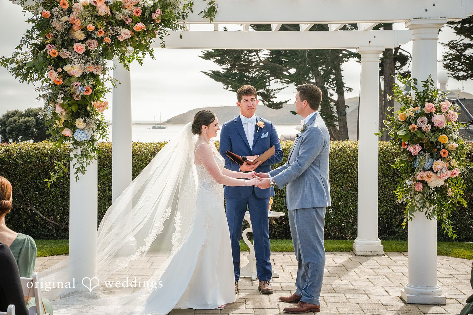 Daniel + Karen A bride and groom standing at an altar under a white pergola during their wedding ceremony.