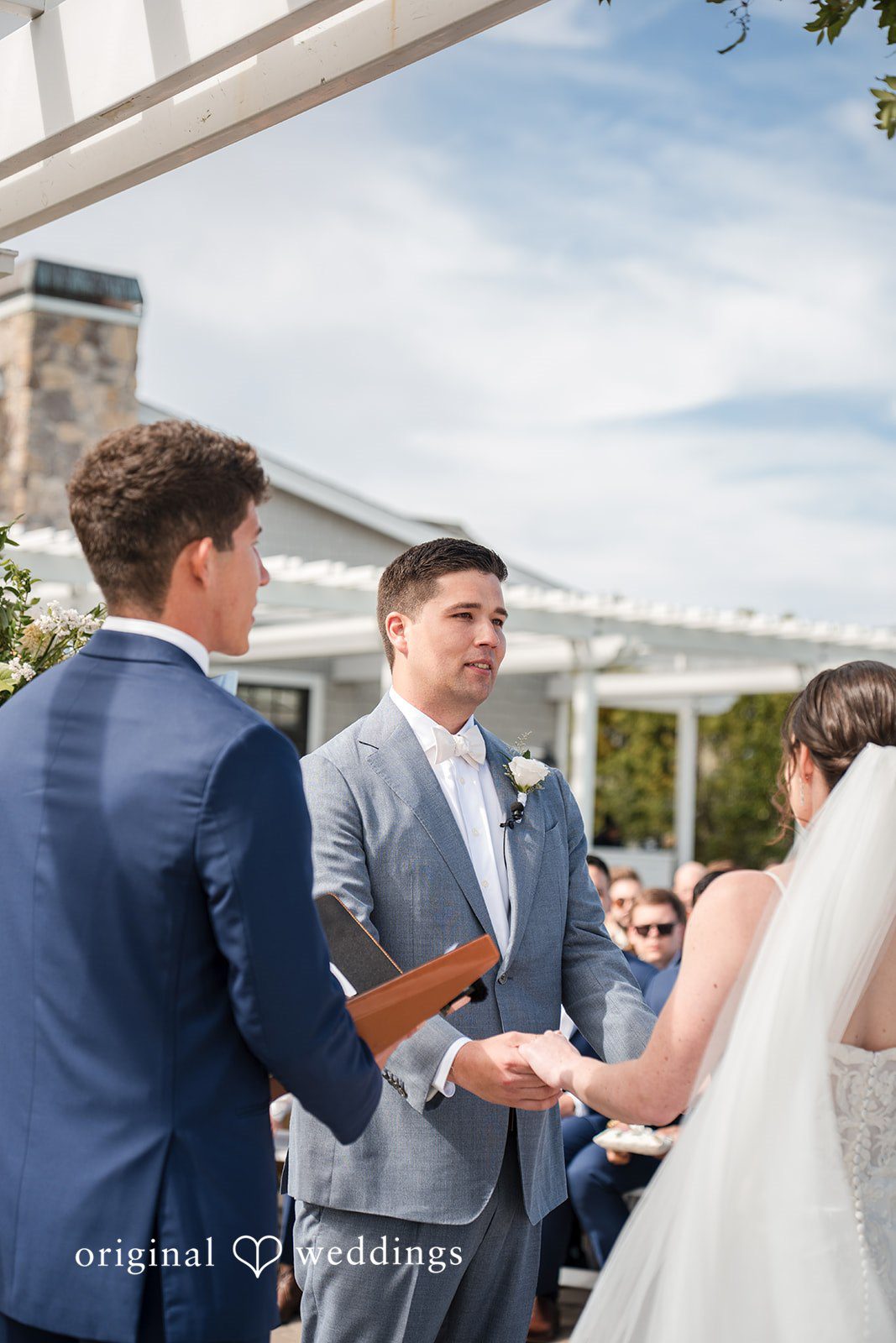 Daniel + Karen A groom exchanging vows with his bride during an open-air wedding ceremony.