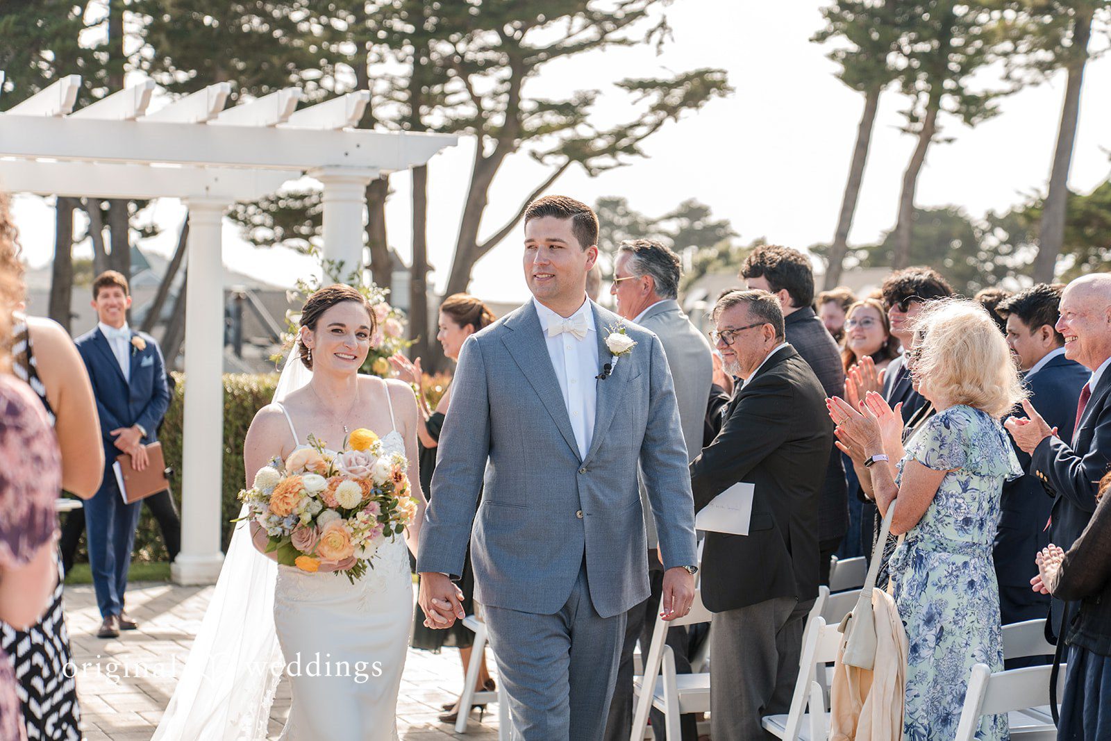 Daniel + Karen A newlyweds walking together down a paved pathway surrounded by guests.