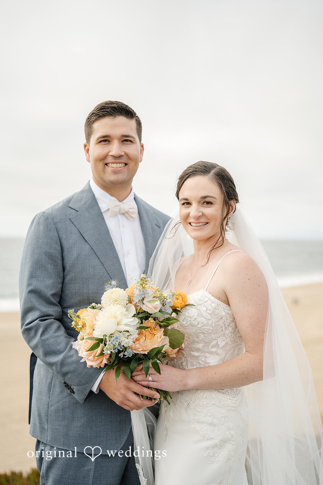 Daniel + Karen A bride and groom smiling while holding a floral bouquet together.